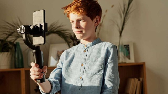 Ein Junge nimmt ein Video mit einem Selfie Stick und einem Handy auf.
